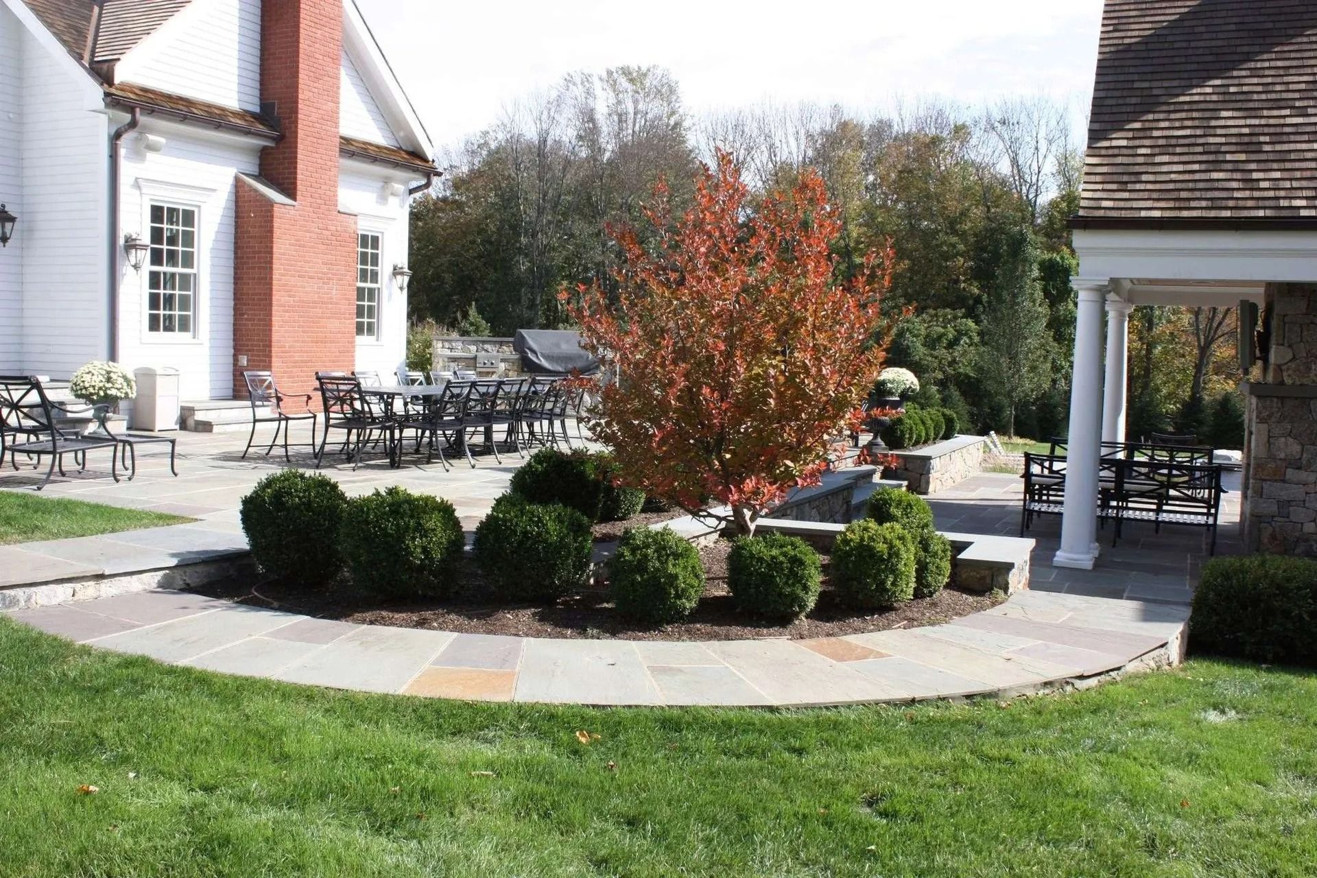 Landscaped courtyard with circular flower bed, shrubs, patio seating, and brick buildings