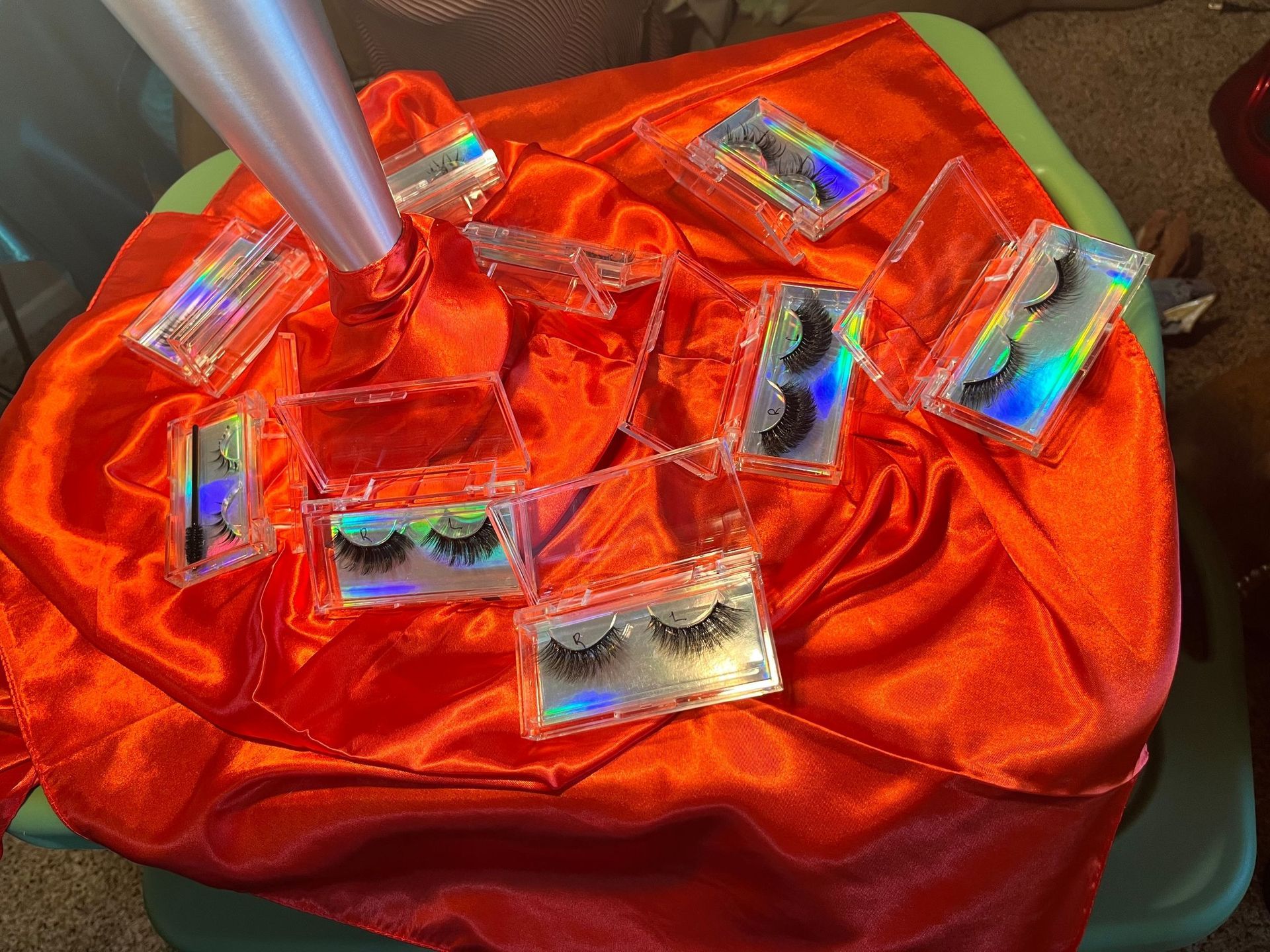 Lashes in clear cases on a red satin cloth. Several boxes are open, one with applicator.