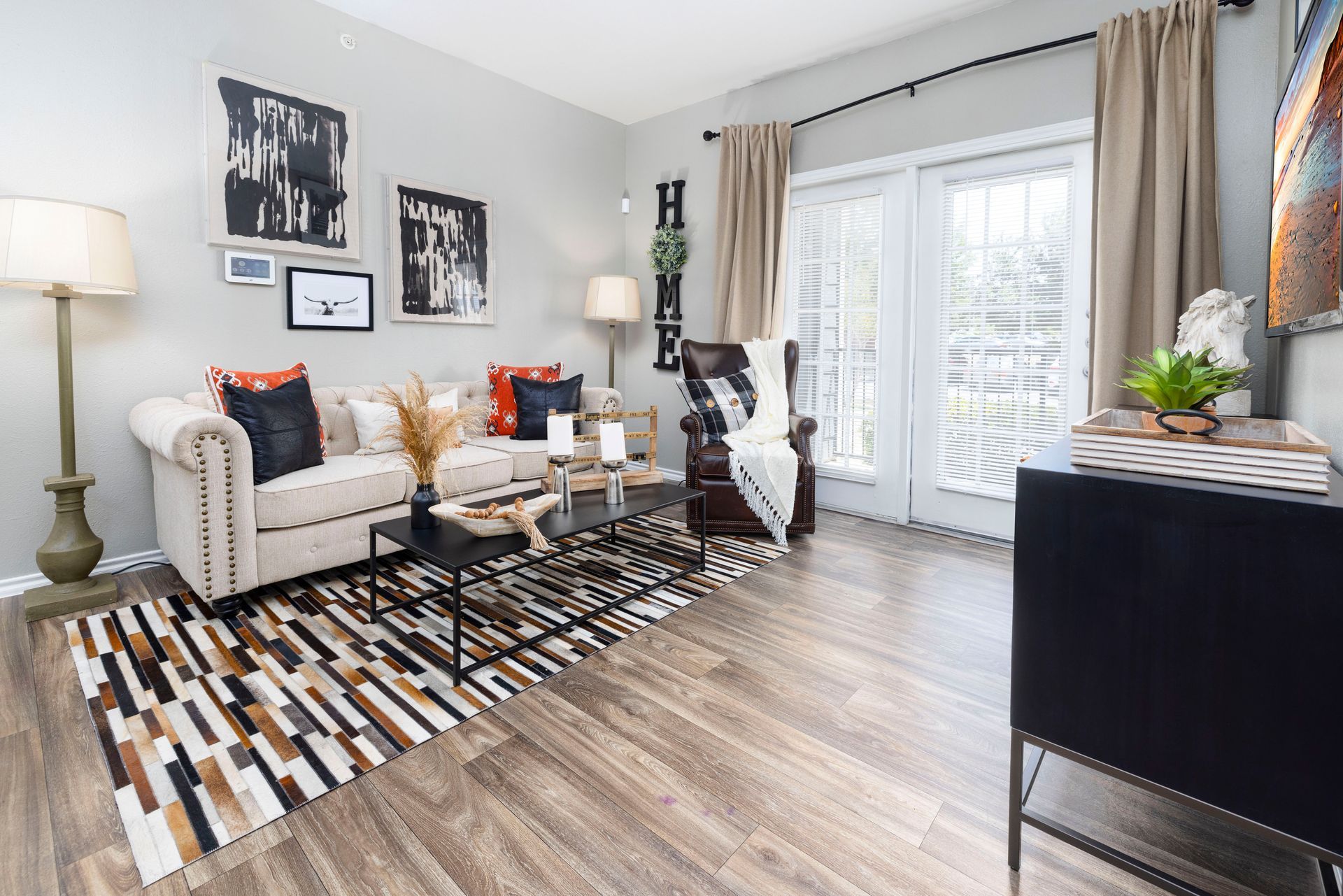 A living room with a couch , chair , rug and sliding glass doors.