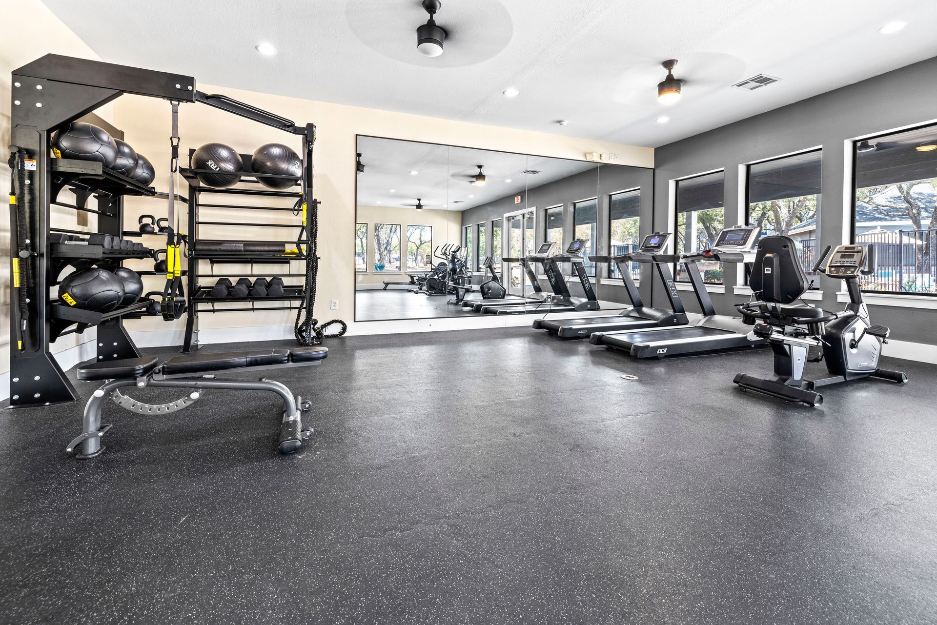 A large swimming pool surrounded by chairs and umbrellas in front of a building.