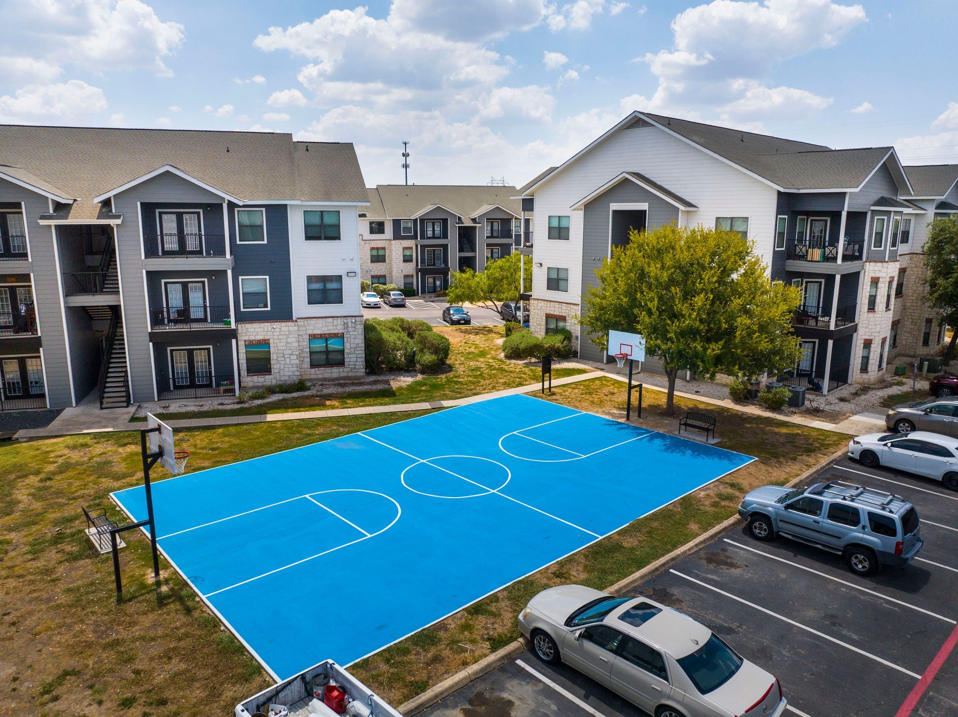 An aerial view of a basketball court in a parking lot in front of a building.
