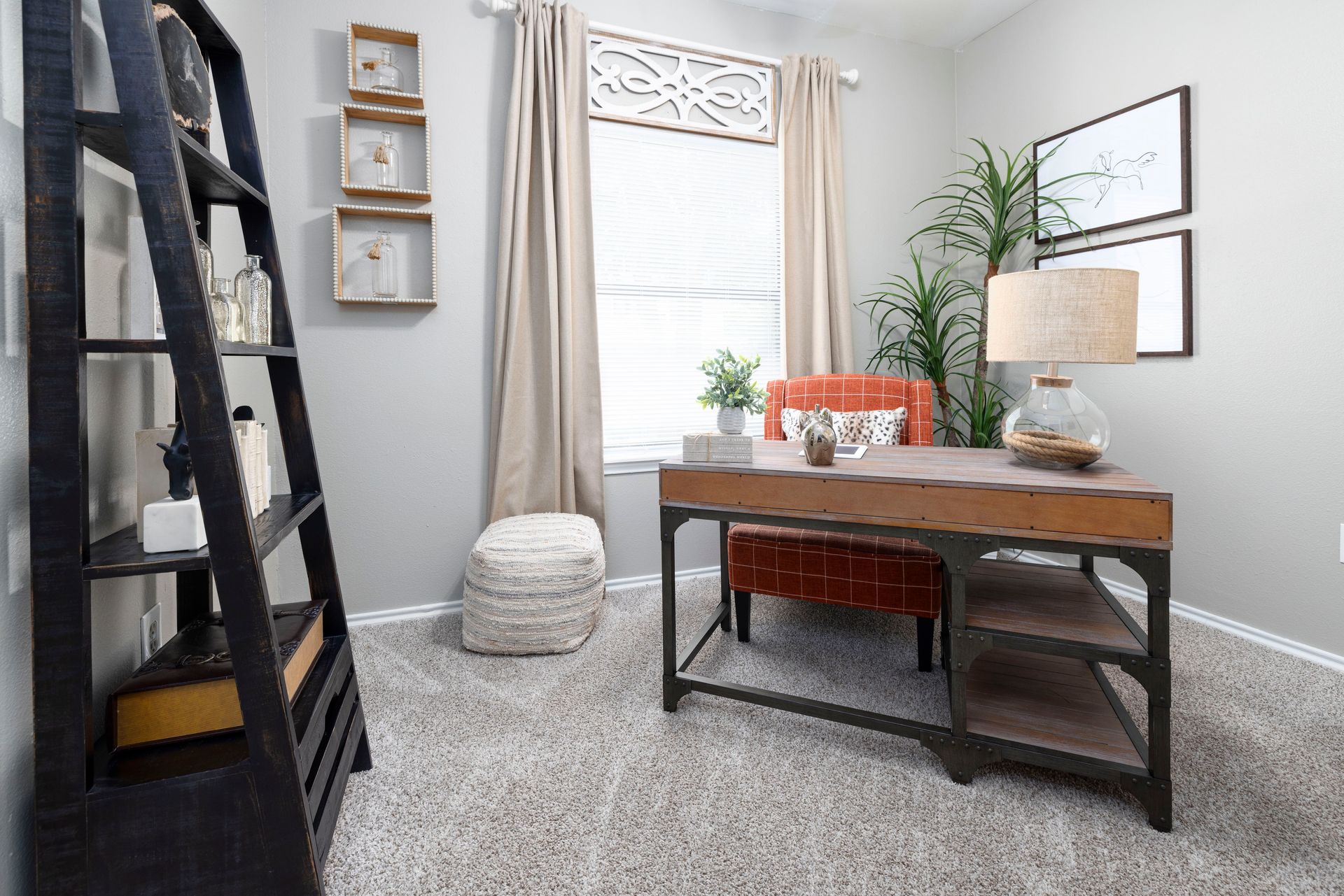 A home office with a desk , chair , lamp and a ladder.