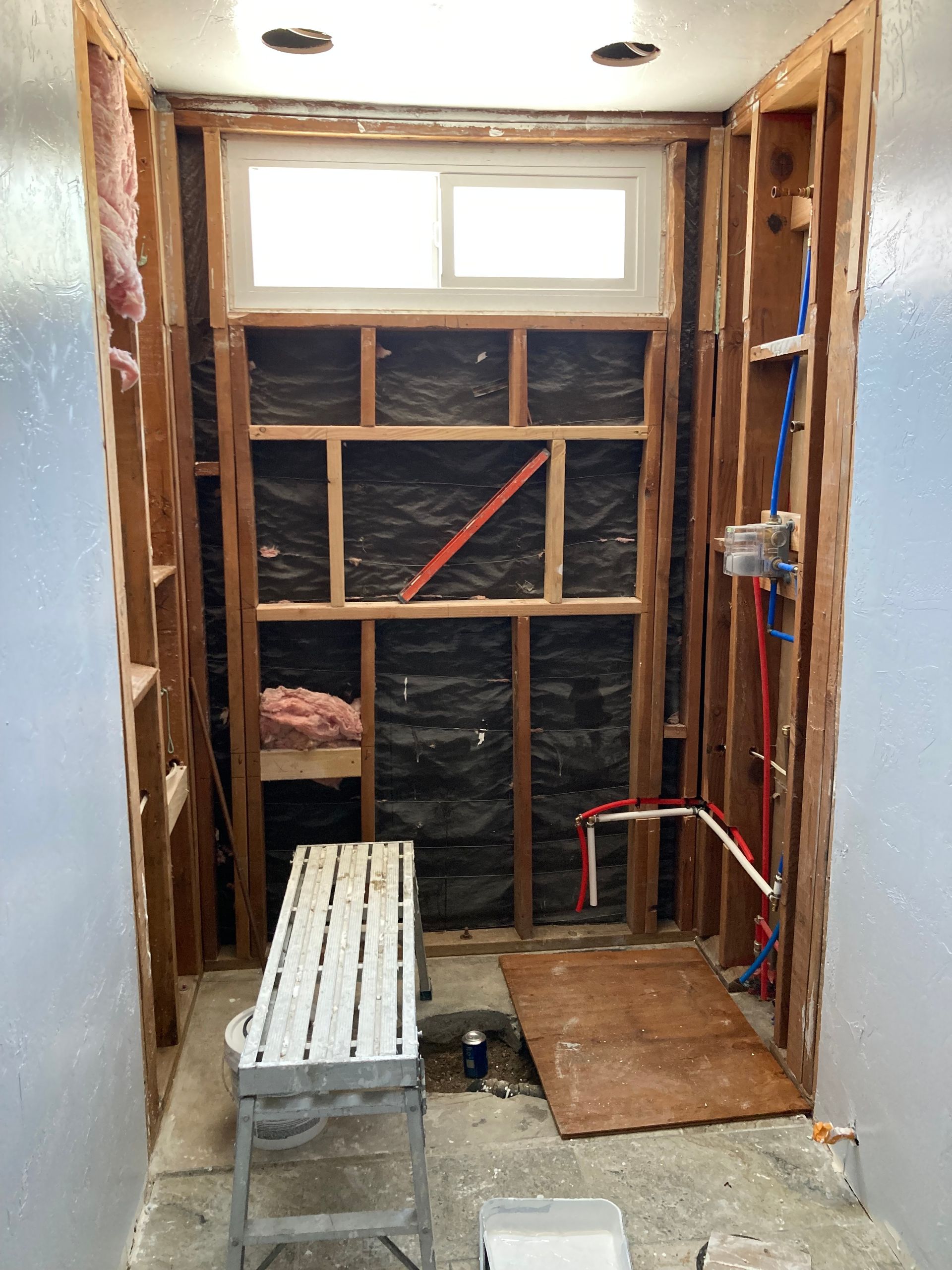 A bathroom under construction with a window and a bench.