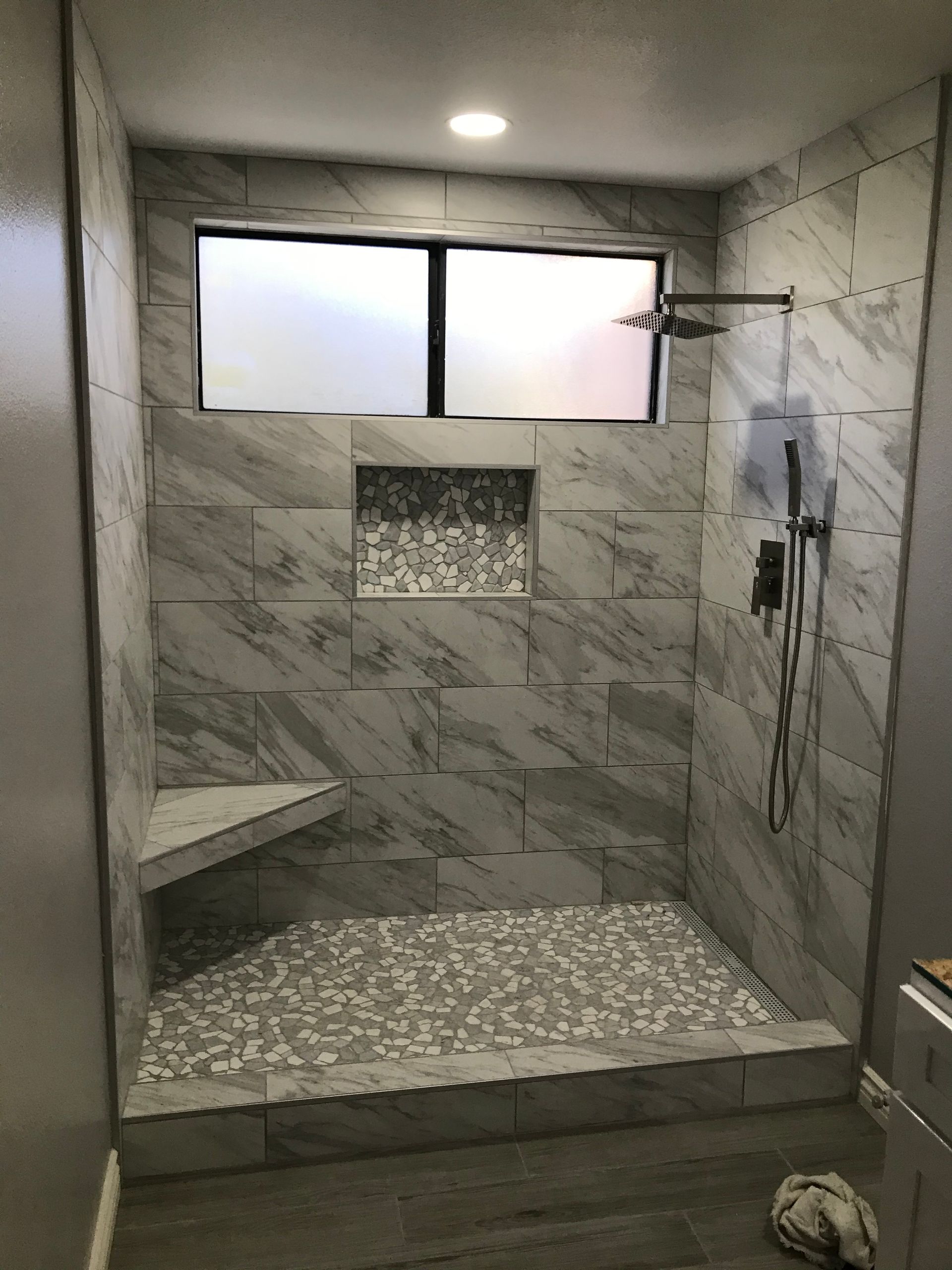 A bathroom with a walk in shower and a window.