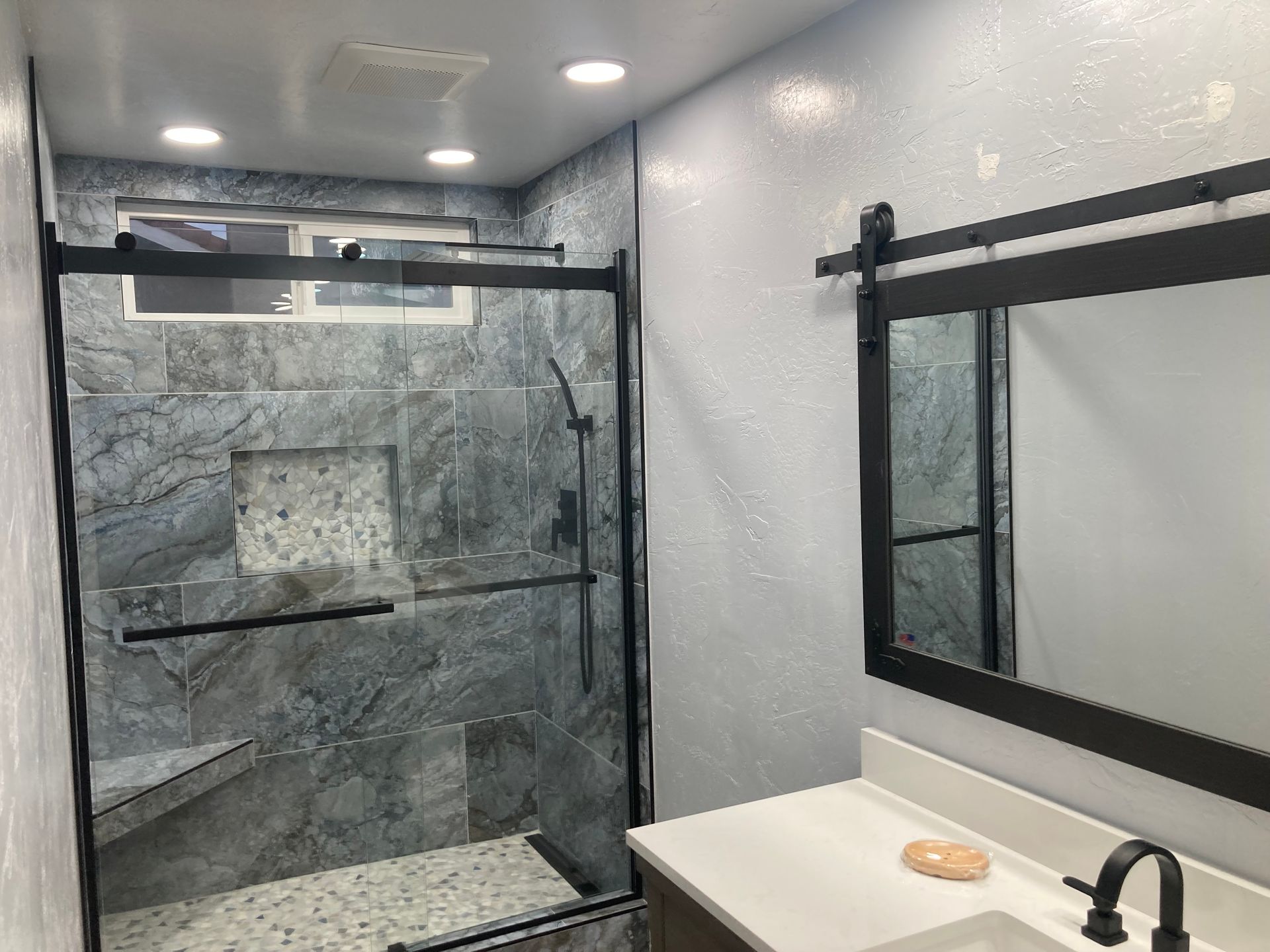 A bathroom with a shower , sink and mirror.