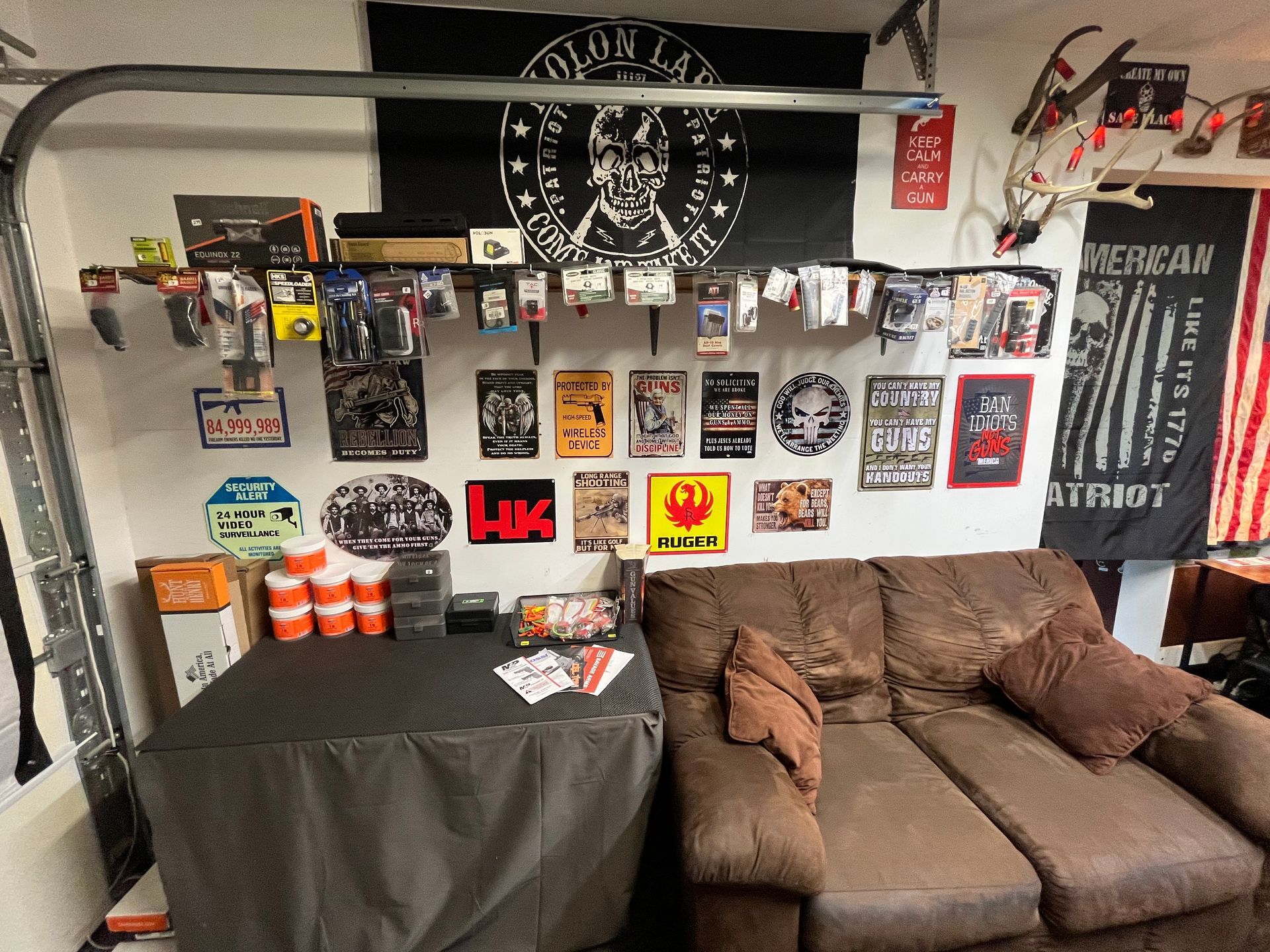 Garage interior with couch, table, and wall decor including flags and posters.