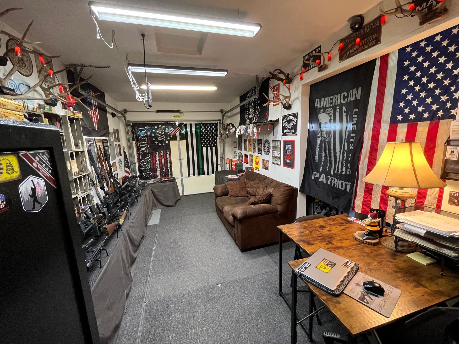 Room with American flags, weapons, a desk, and a couch; likely a patriotic display.