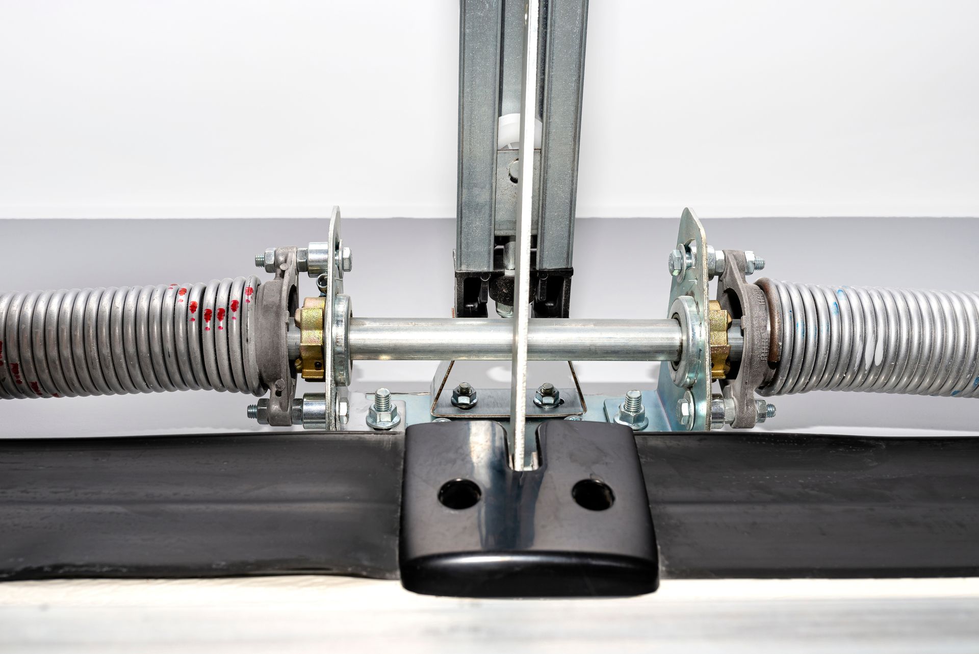 Interior view of garage door mechanism with visible rail, chain, and tensioned springs.