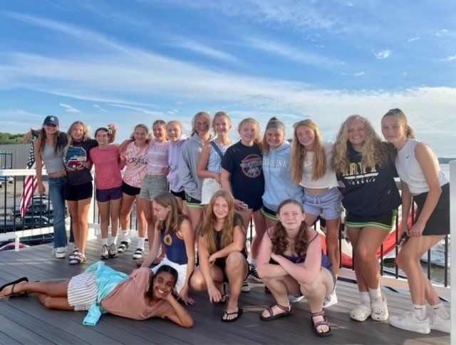 A group of young girls are posing for a picture on a deck.