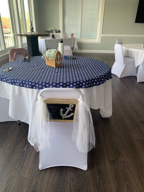 A table with a blue and white table cloth and white chairs