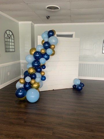 A room filled with blue and gold balloons and a white wall.