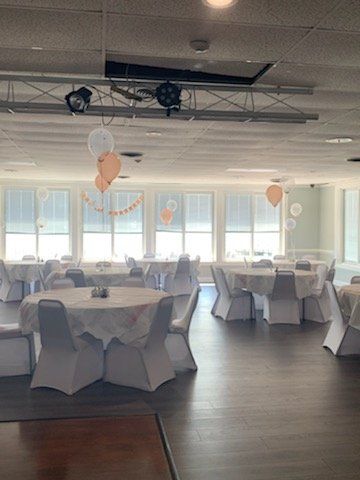 A large room with tables and chairs and balloons hanging from the ceiling.