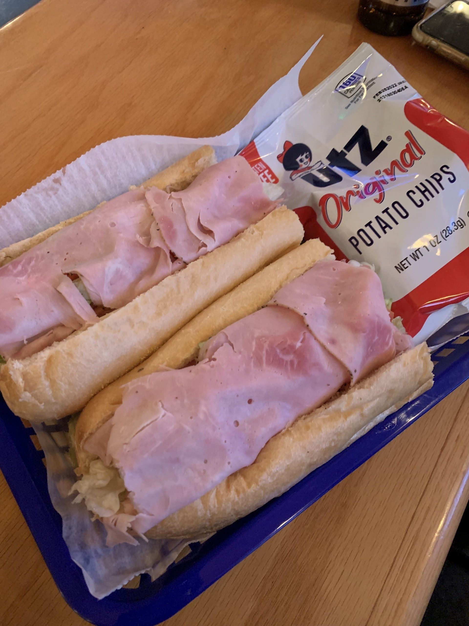A bag of ritz original potato chips sits next to a sub sandwich