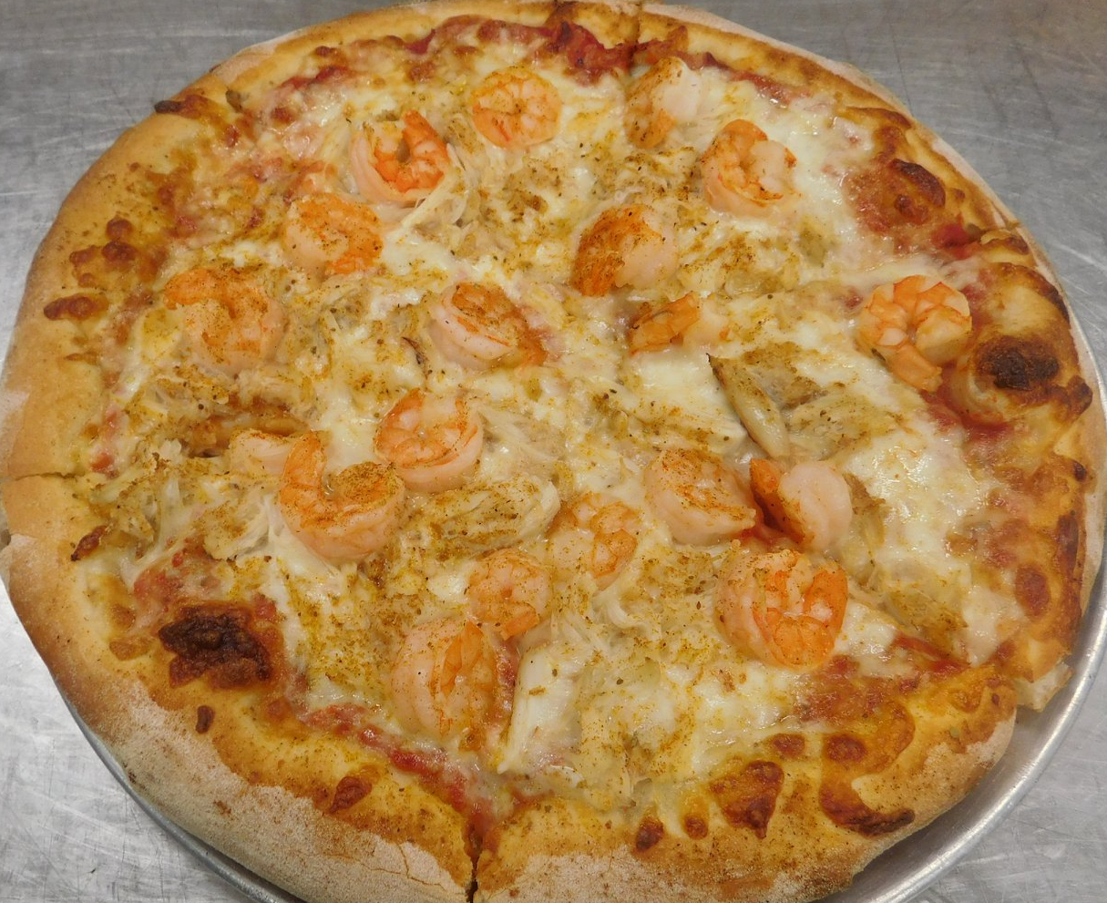A pizza with shrimp and cheese on a pan on a table.