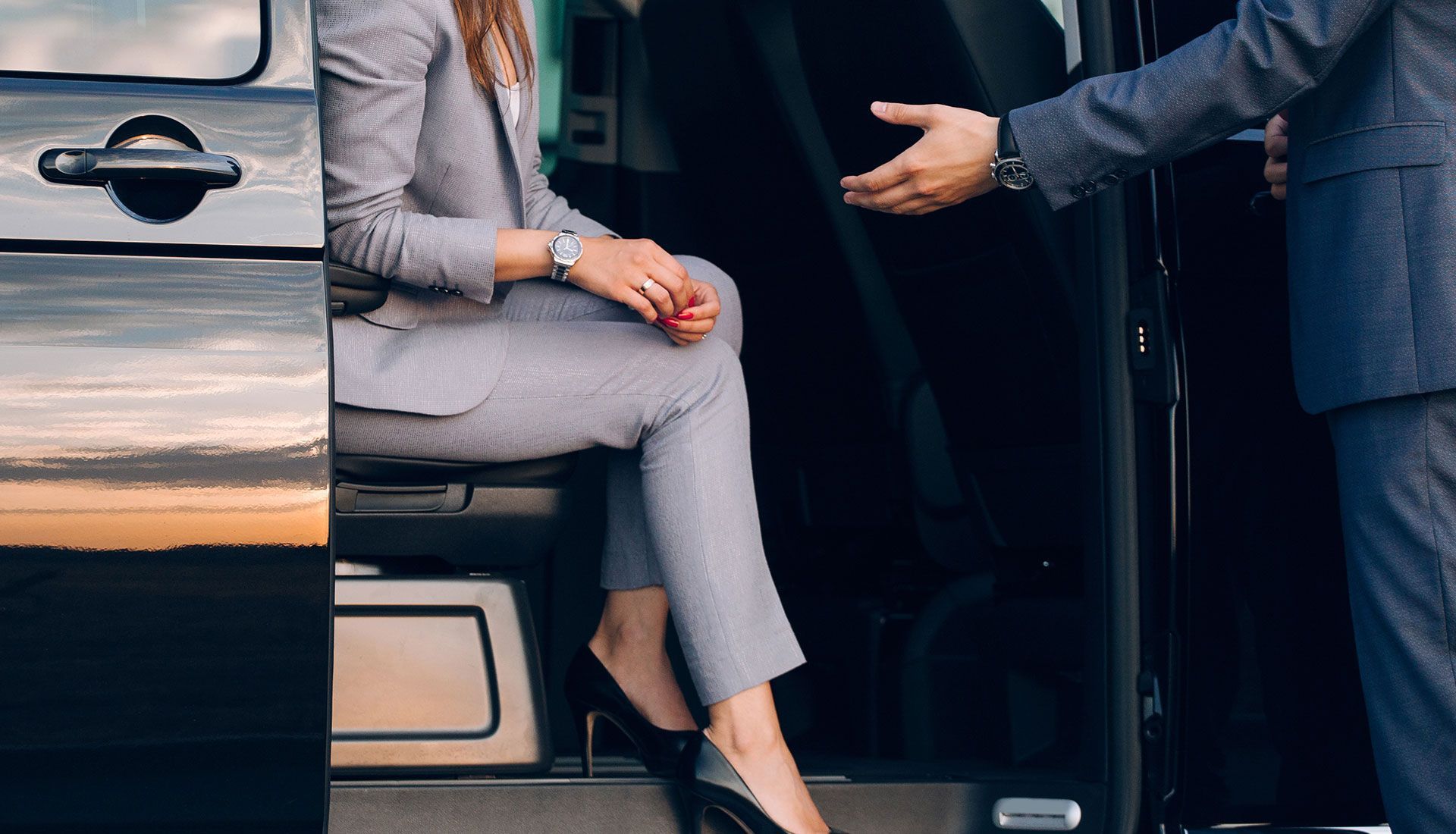 Person painting the trim of a house window, wearing white clothing, sunny day.