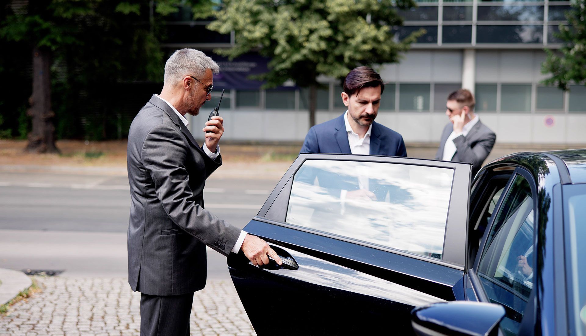 Person painting the trim of a house window, wearing white clothing, sunny day.