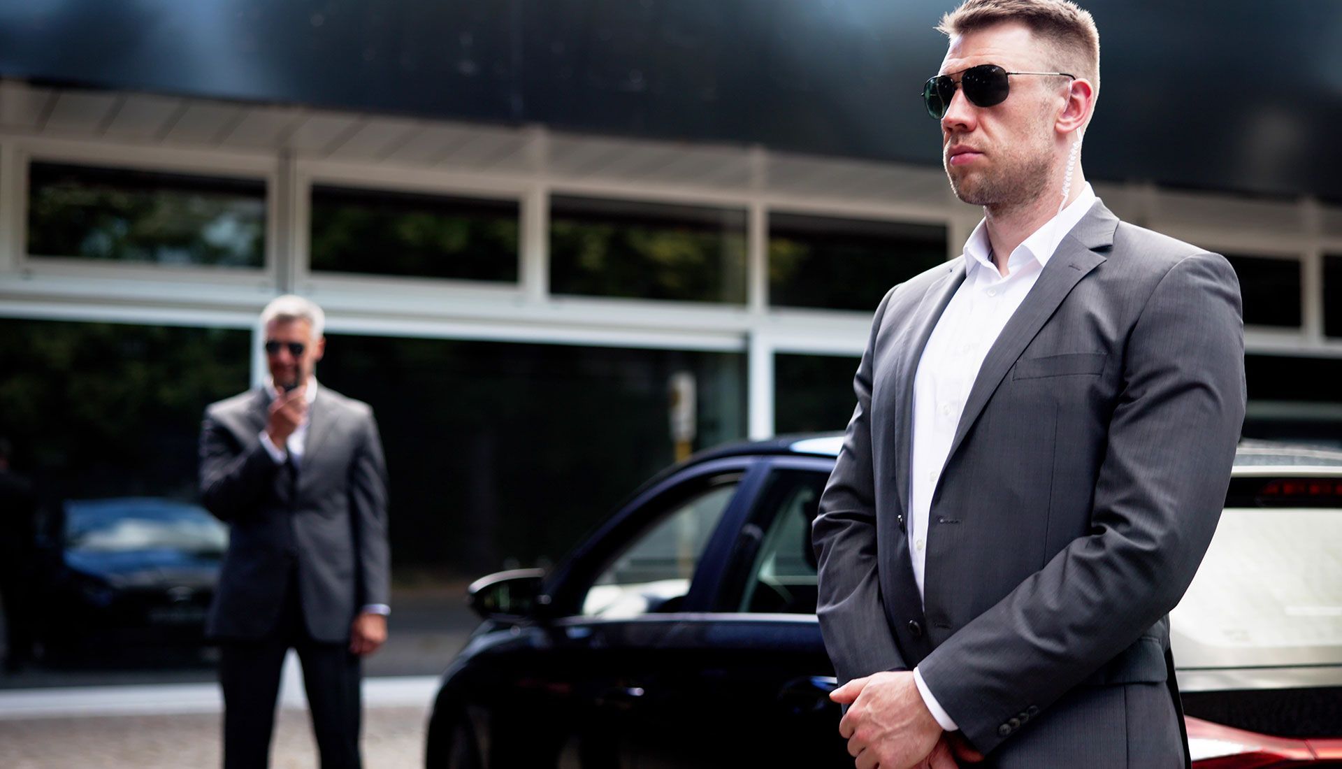 Person painting the trim of a house window, wearing white clothing, sunny day.