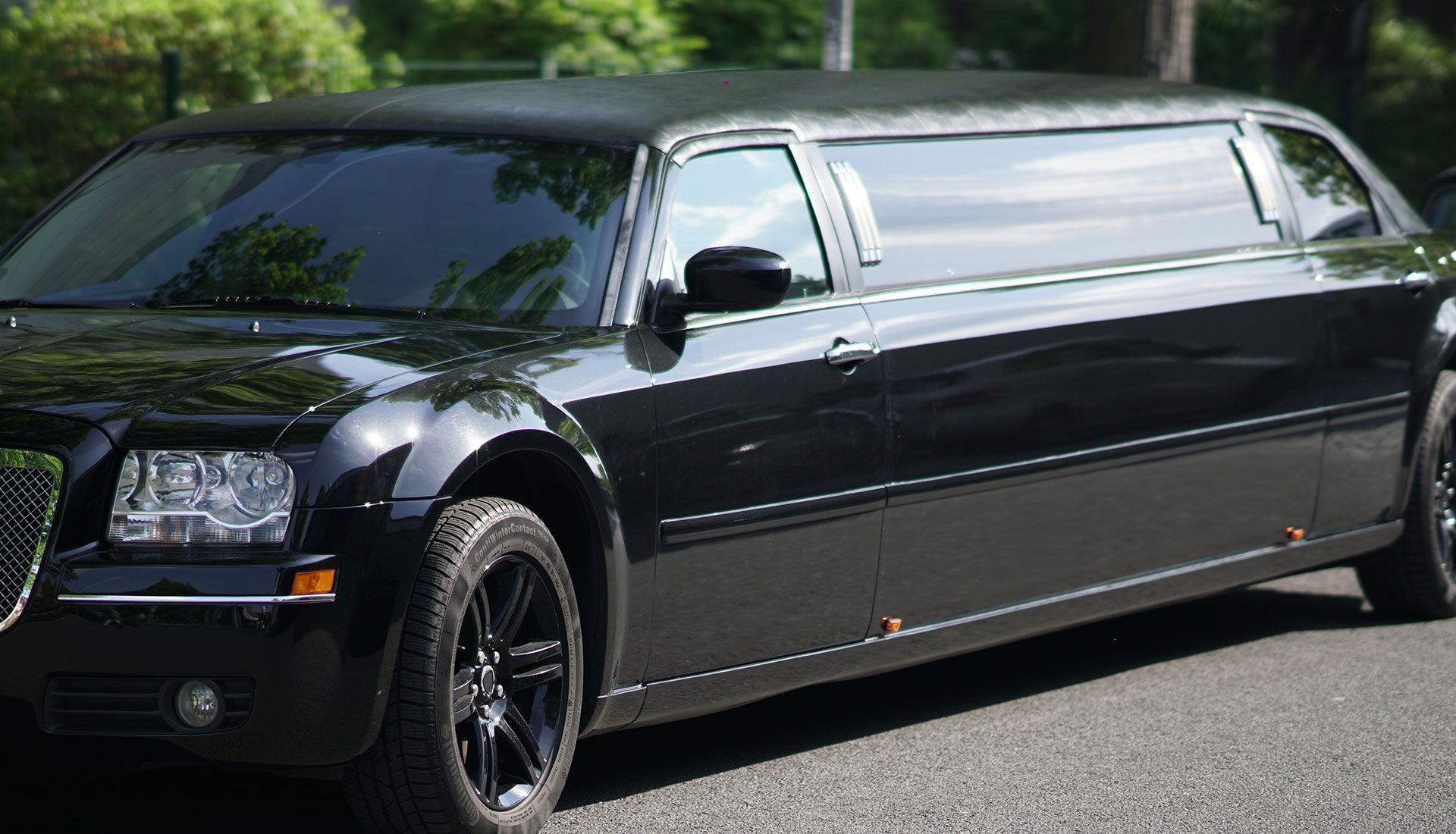 Person painting the trim of a house window, wearing white clothing, sunny day.