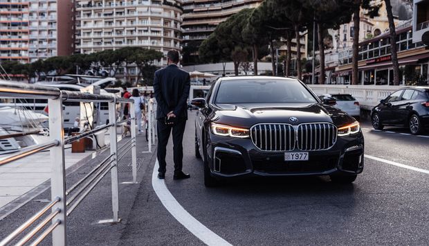 Person painting the trim of a house window, wearing white clothing, sunny day.
