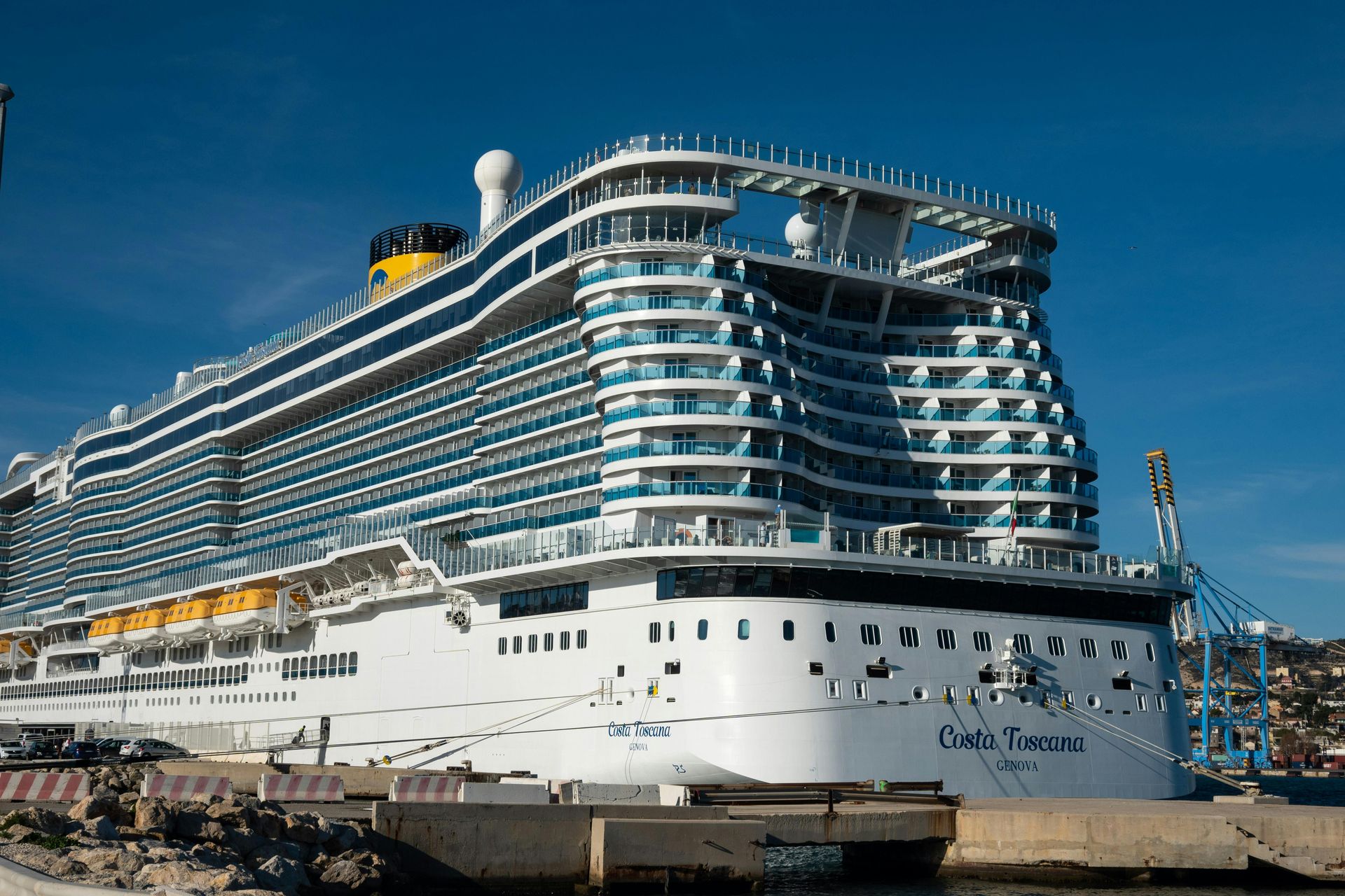 Person painting the trim of a house window, wearing white clothing, sunny day.