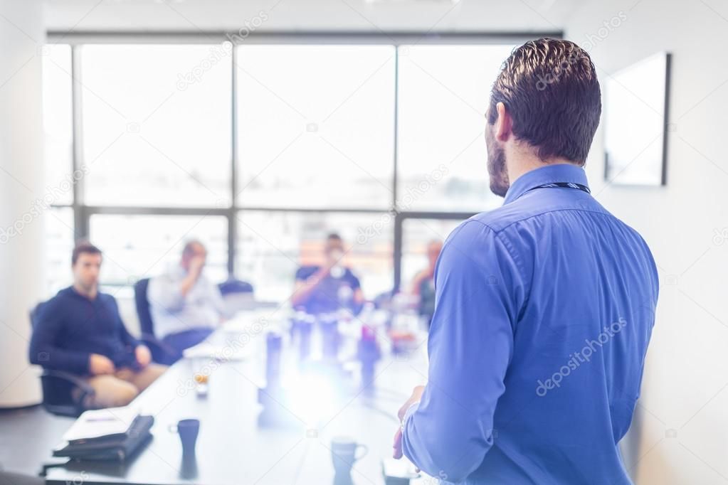 A man is giving a presentation to a group of people in a conference room.