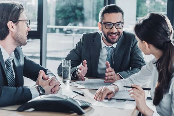 A group of business people are sitting around a table having a meeting.