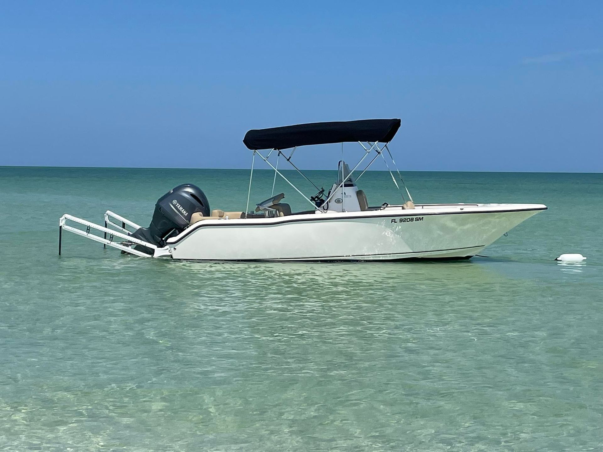 A white boat with a black canopy is in the ocean