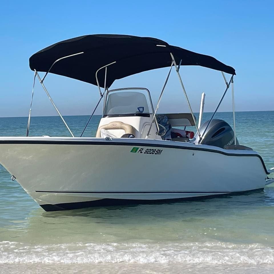 A white boat with a black canopy and florida license plate