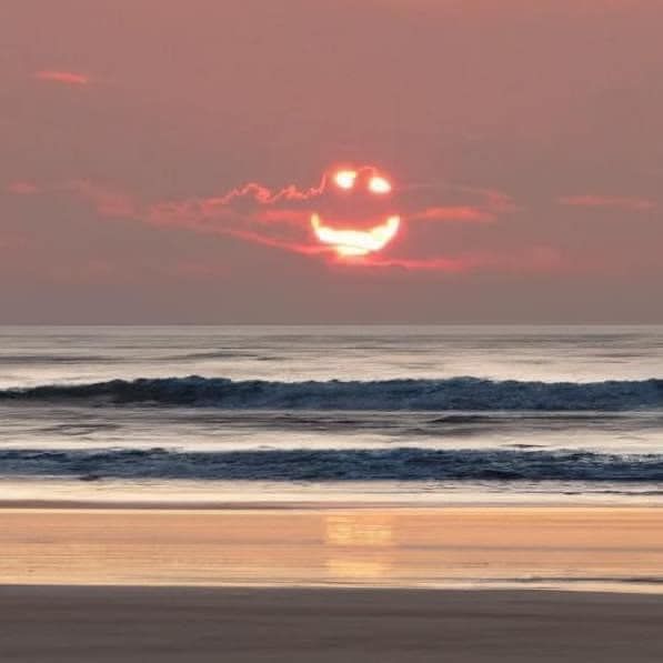 A sunset over the ocean with a smiley face in the sky