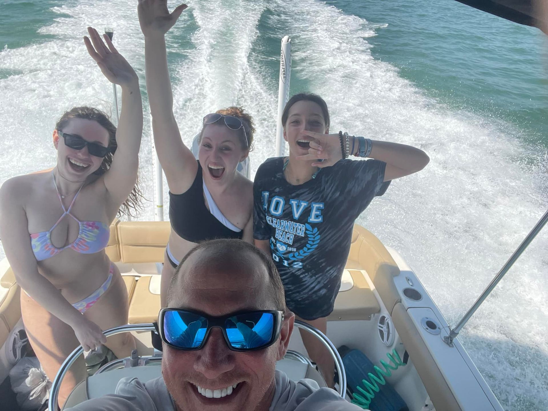 A man and two women are on a boat in the ocean.