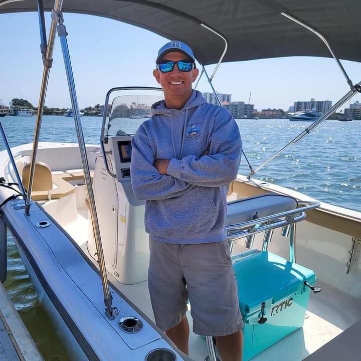 A man is standing on a boat with his arms crossed