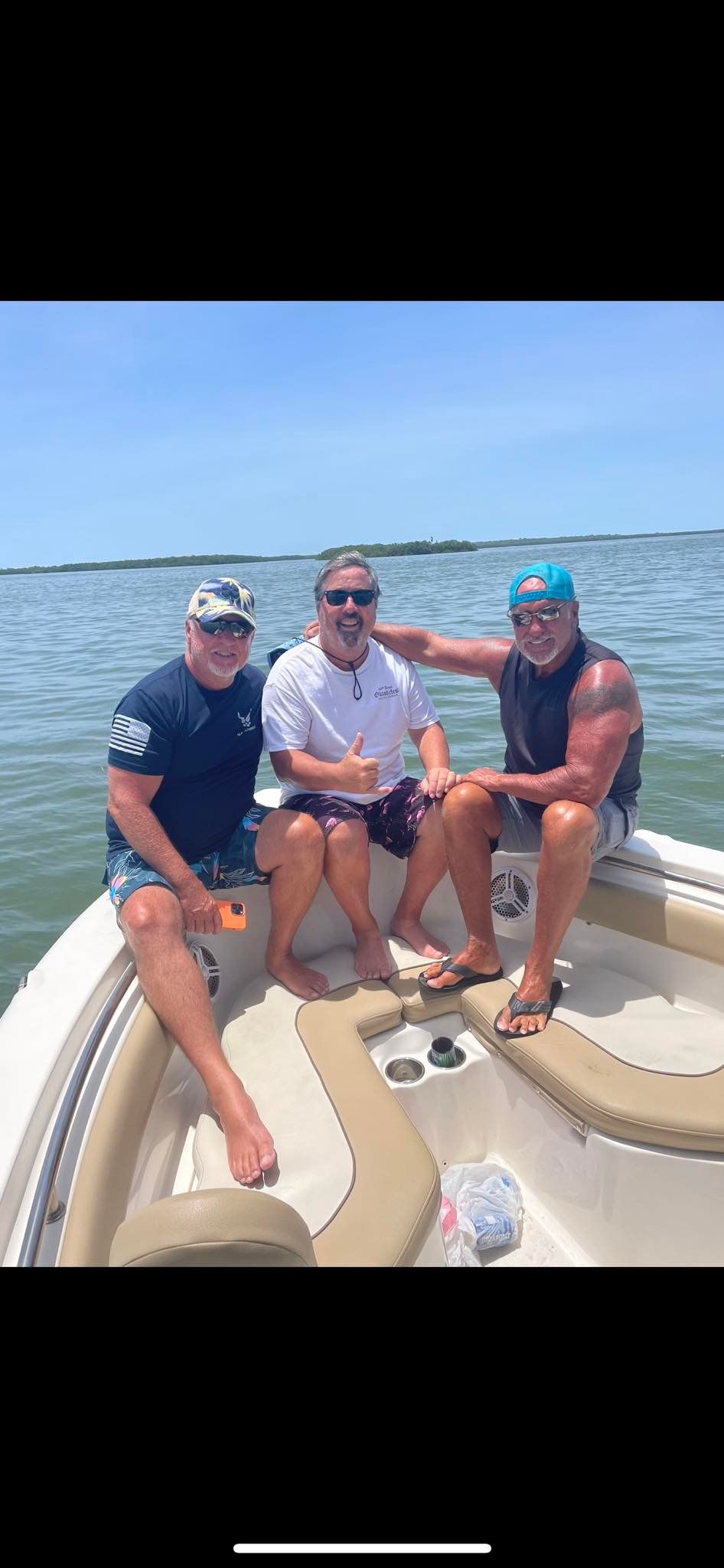 Three men are sitting on a boat in the water.