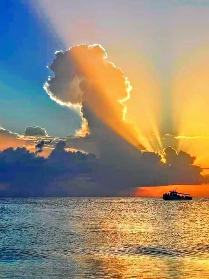 The sun is shining through the clouds over the ocean