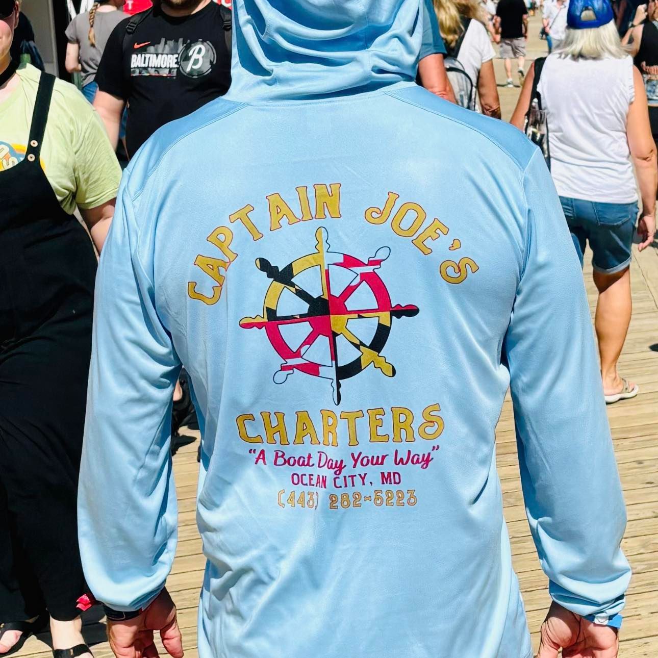 A person wearing a captain joe 's charters shirt