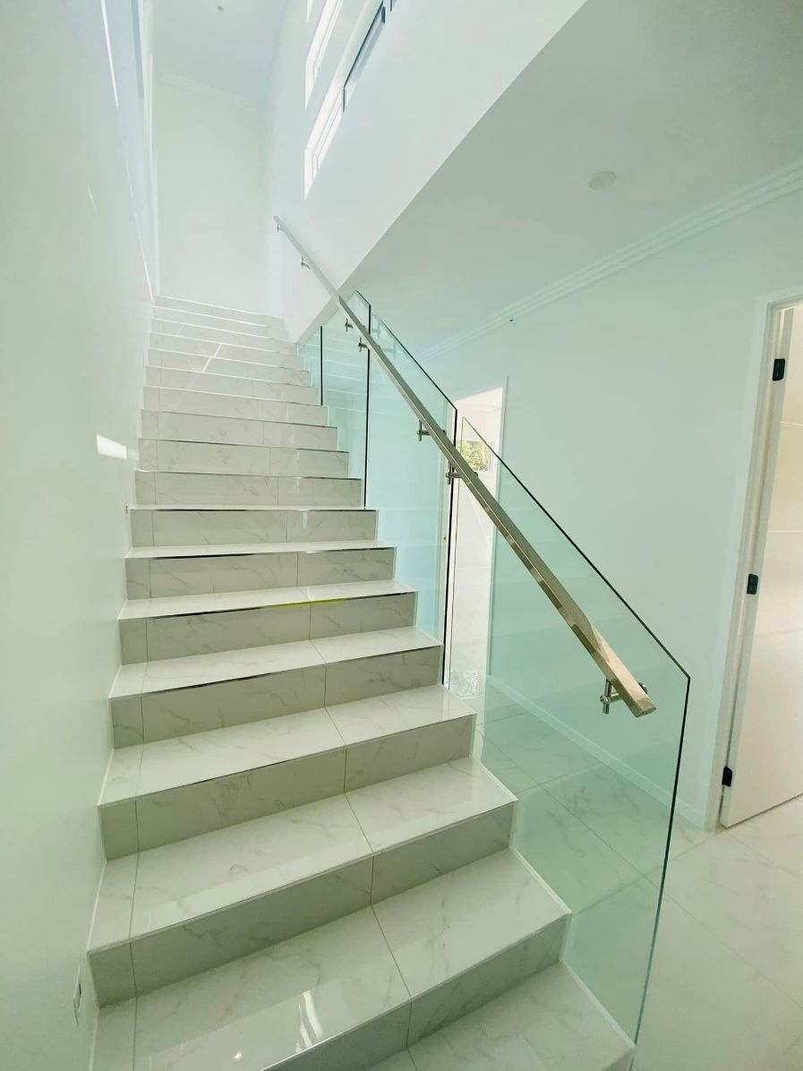 A Staircase With A Glass Railing And A Wooden Handrail — Ward's Aluminium in Garbutt, QLD