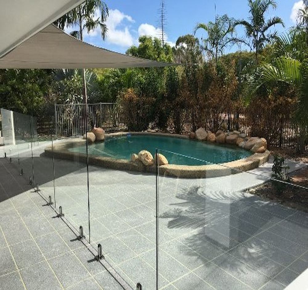 A Large Swimming Pool With A Glass Fence Around It — Ward's Aluminium in Garbutt, QLD