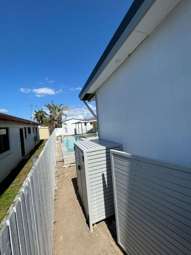 A White Fence Surrounds A House With A Pool In The Background — Ward's Aluminium in Garbutt, QLD