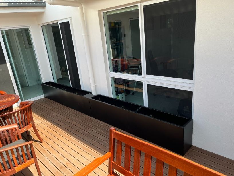 A Wooden Bench Is Sitting On A Wooden Deck Next To A Window — Ward's Aluminium in Garbutt, QLD
