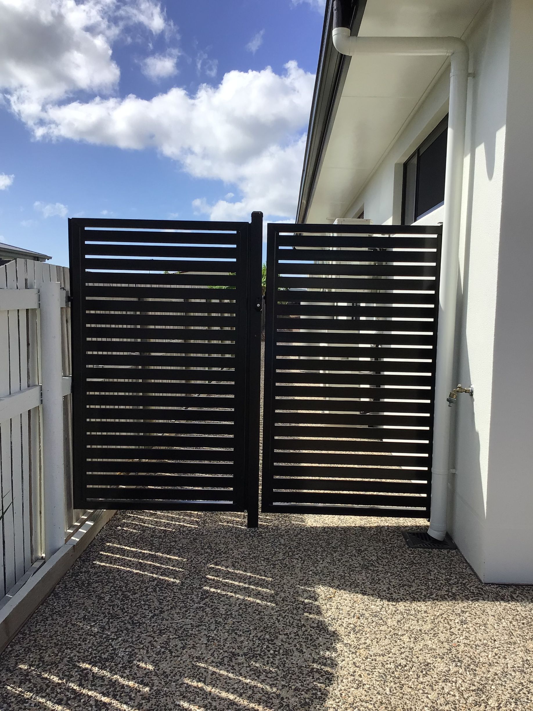 A Black Frame Fence with a blue sky and clouds in the background— Ward's Aluminium in Townsville, QLD
