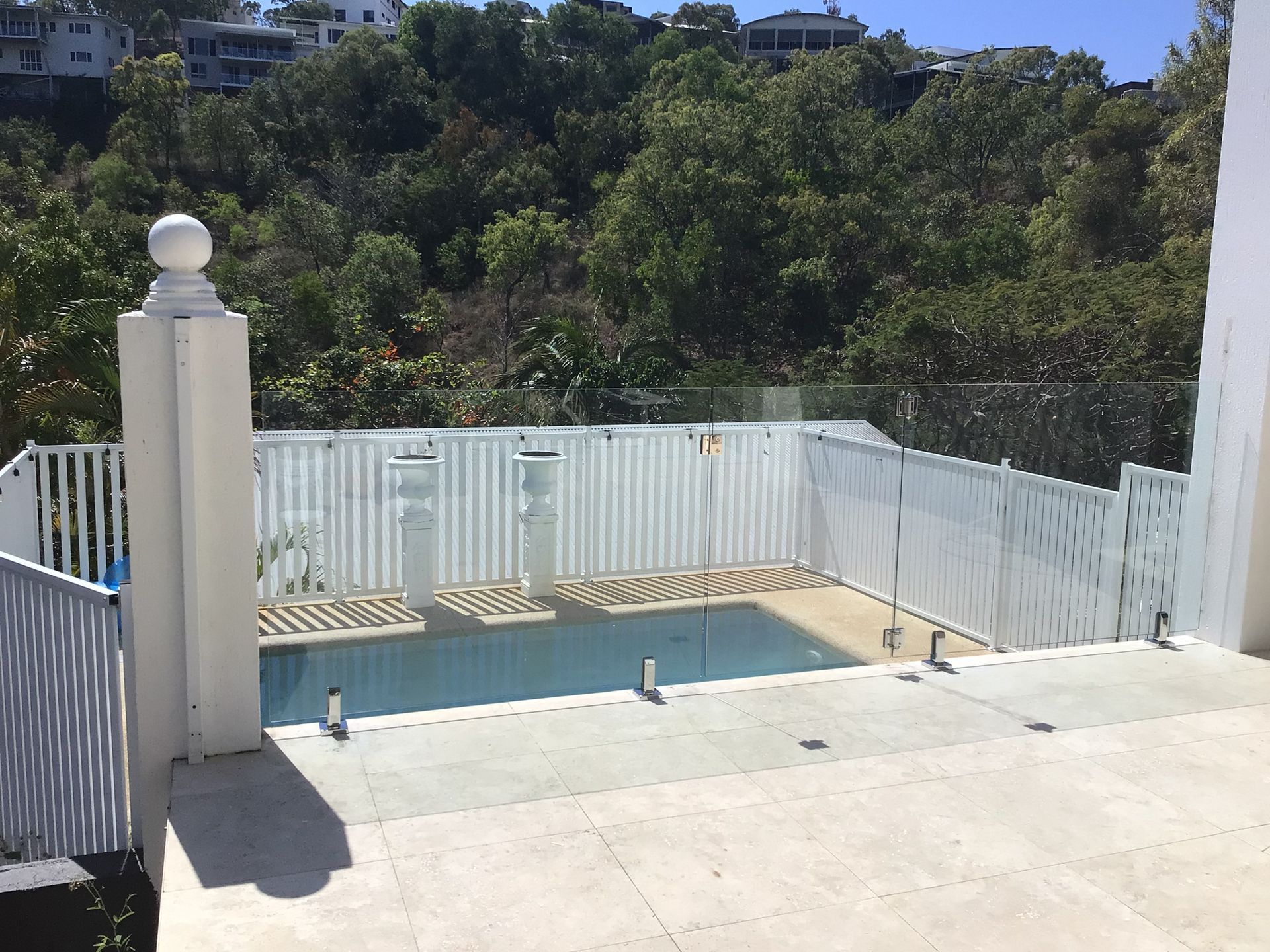 A Swimming Pool surrounded by a White Fence and a Glass Fence  — Ward's Aluminium in Garbutt, QLD