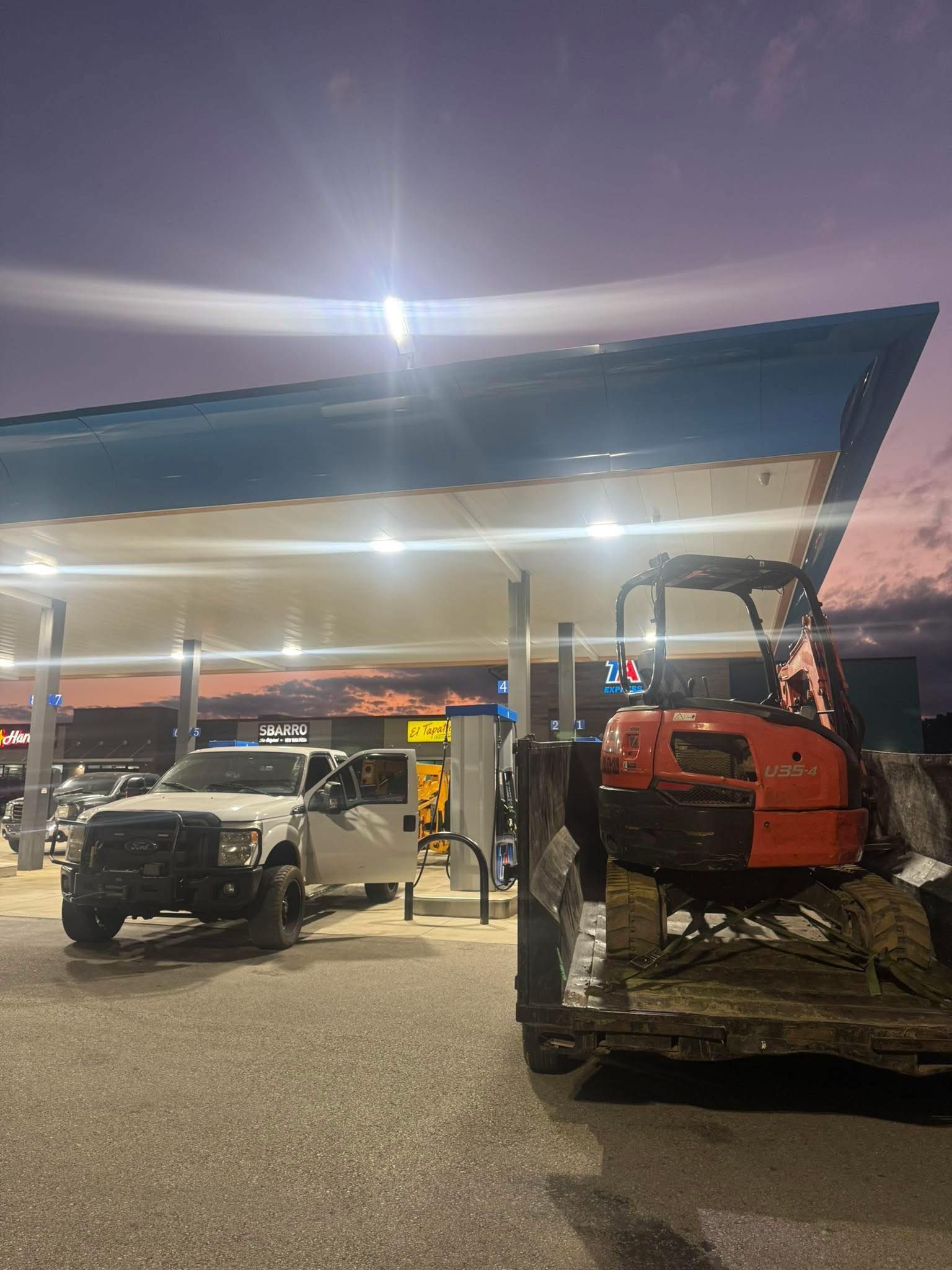Woman in straw hat smiles, holding wine glass near a lake.
