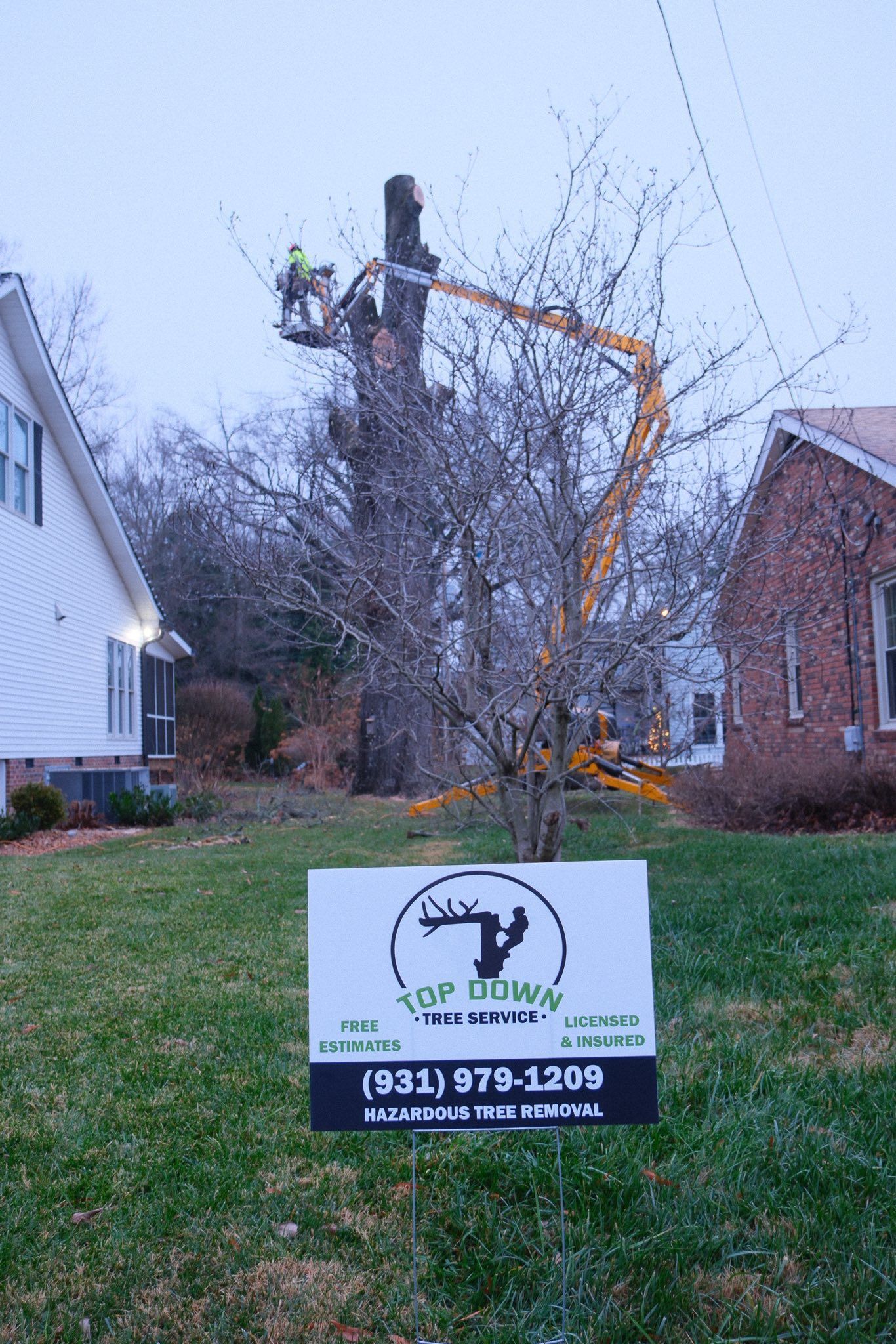 Woman in straw hat smiles, holding wine glass near a lake.