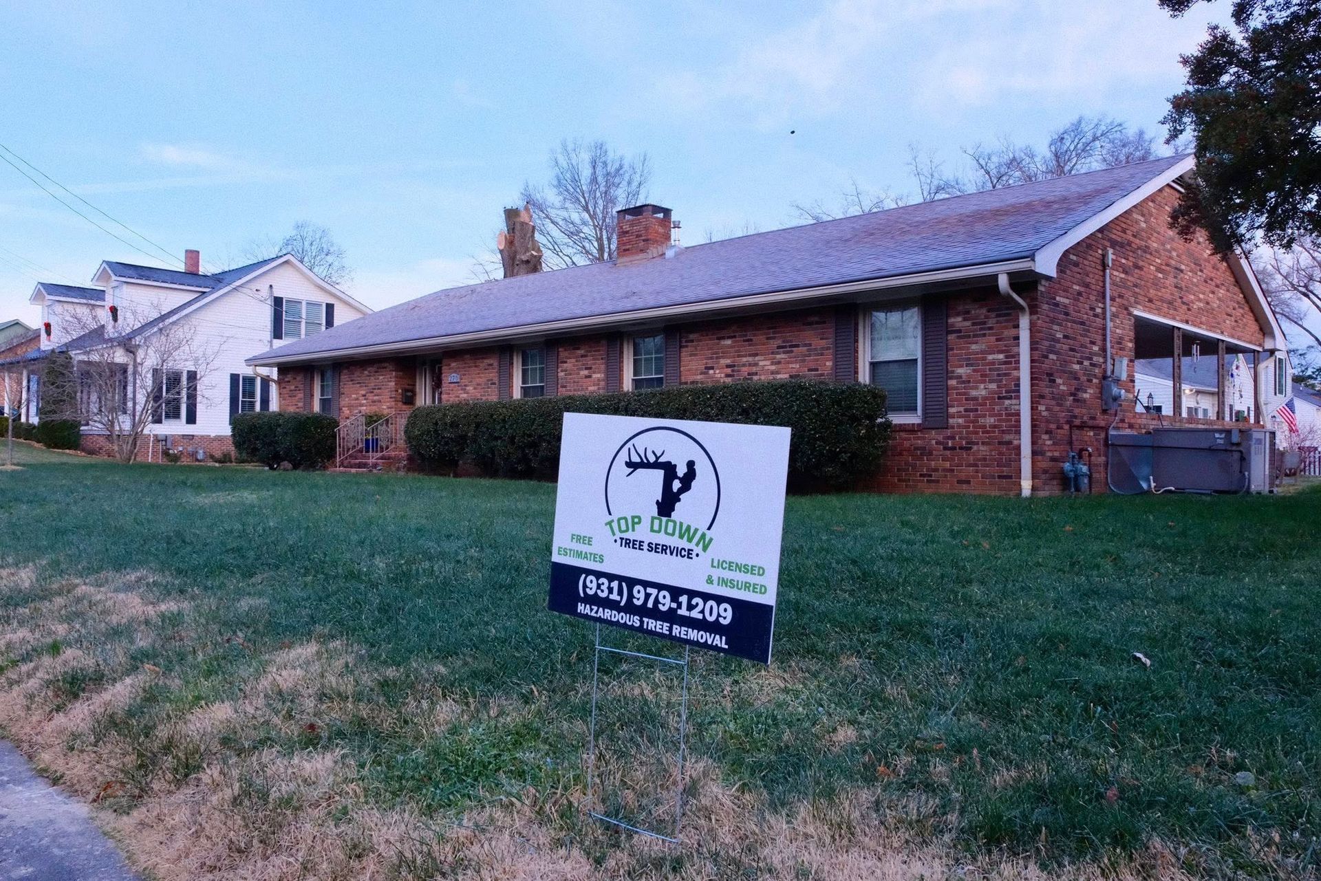 Woman in straw hat smiles, holding wine glass near a lake.