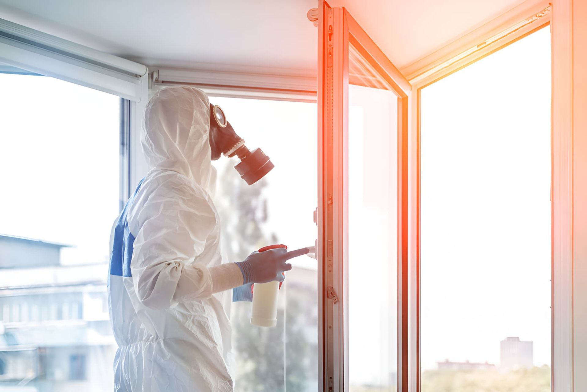 A Man in a Protective Suit and Gas Mask is Cleaning a Window — Veramax Industries in Whitsundays, QLD