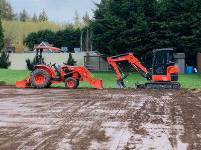A tractor and an excavator are working on a dirt field