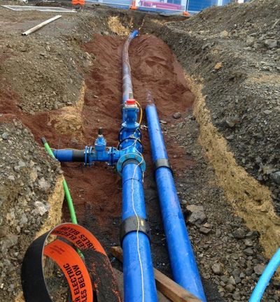 A blue pipe is being installed in a trench
