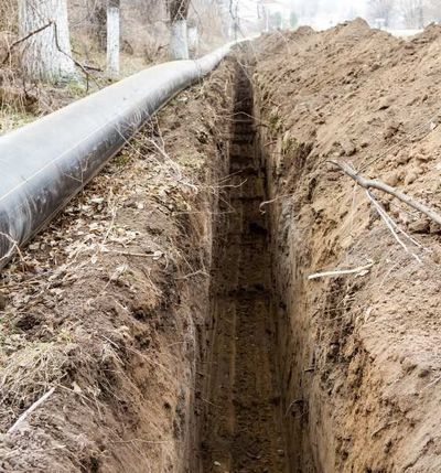 A pipe is being installed in a trench next to a road.