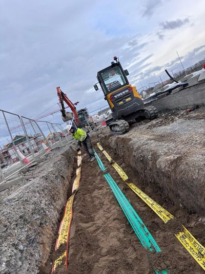 A construction site with a volvo excavator digging a trench.
