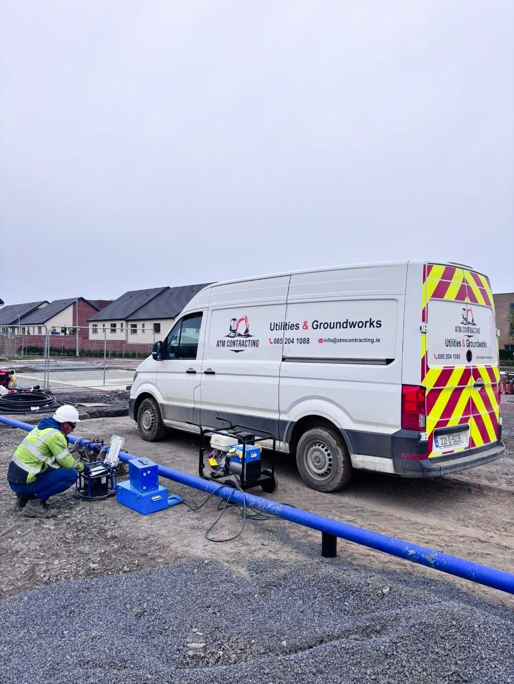 A man is working on a pipe next to a van.