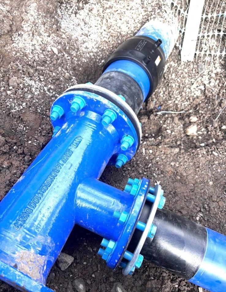 Blue metal pipe fittings joined with black connectors and bolts, outdoors.